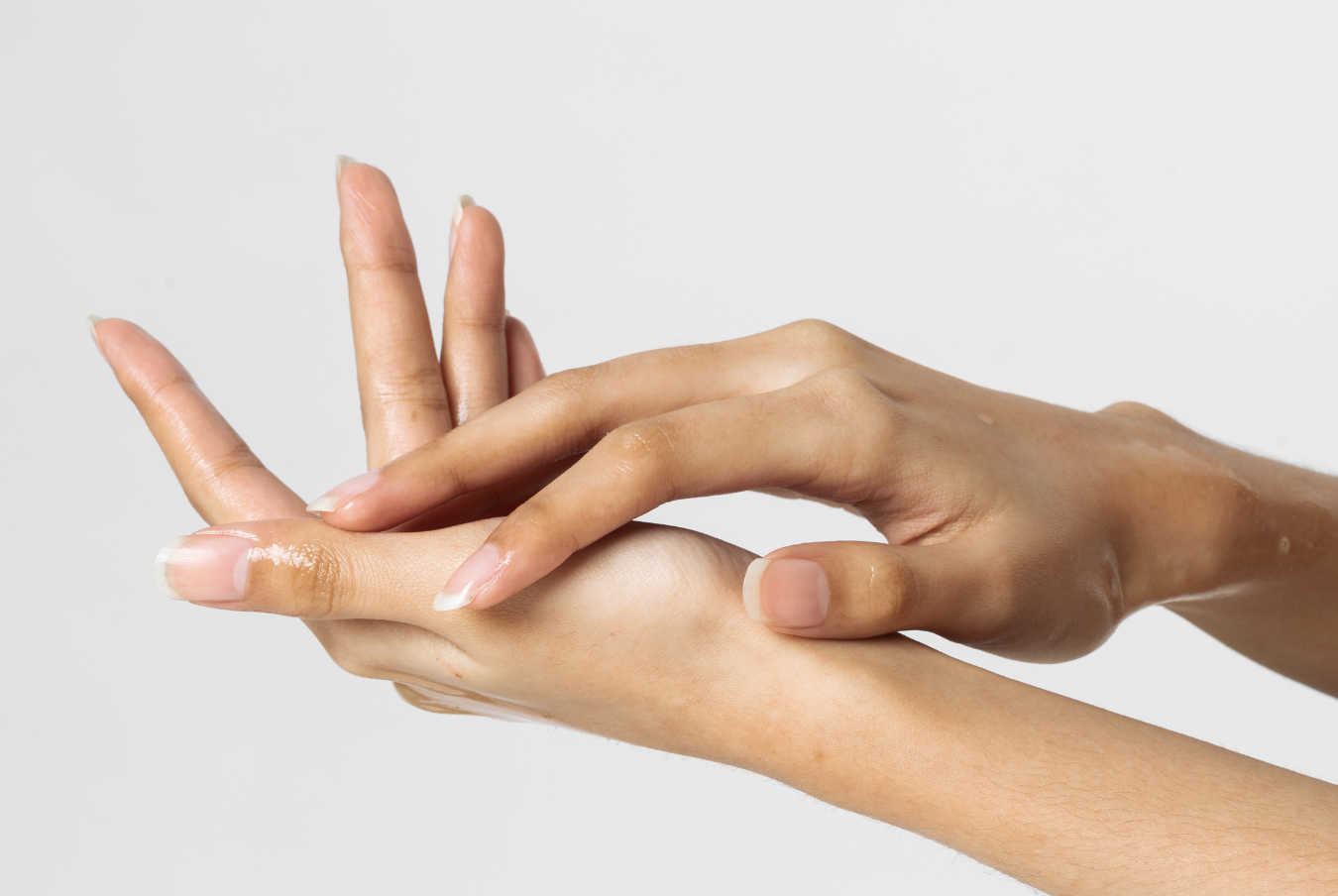 Close-up of hands with moisturized skin on a light background
